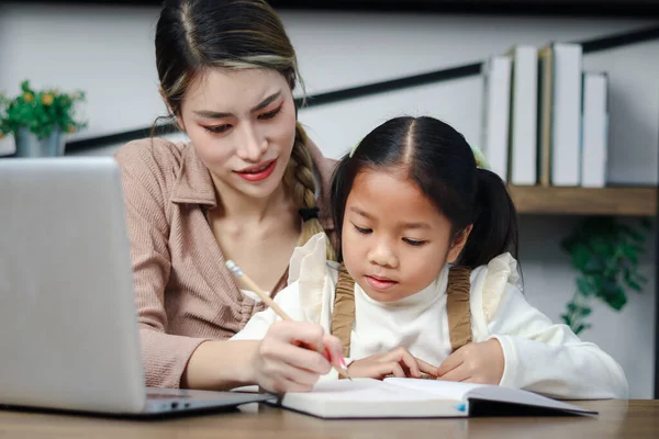 亚洲女孩在家里用笔记本电脑与母亲上网 女学生在网上远程学习 在家里与家庭教师一起做作业 学生学习和写作 儿童教育 — 图库照片