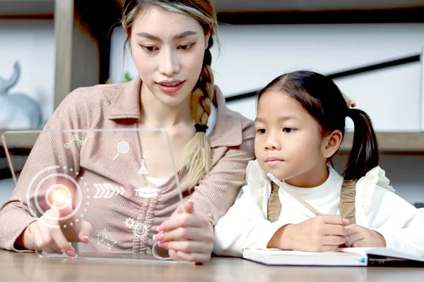 亚洲女孩在家里和妈妈一起学习技术课程 妈妈触摸透明设备 触摸教育图标屏幕 用透明平板电脑学习 聪明进步的孩子访问It课程 — 图库照片