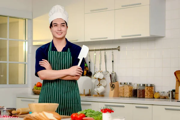 Uomo asiatico che indossa cappello e grembiule da chef sorride