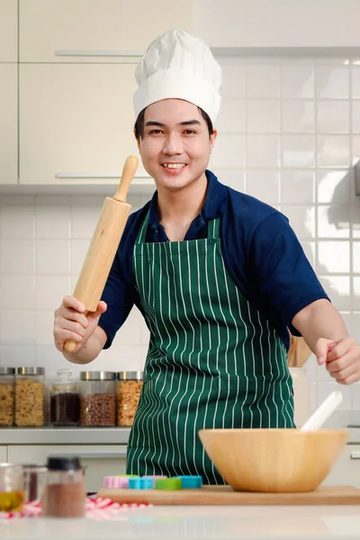 Portret Młodego Uśmiechniętego Azjaty Fartuchem Czapką Szefa Kuchni Trzymającego Drewniany — Zdjęcie stockowe
