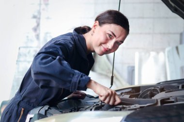 Garajda motorlu araçla çalışan güzel kadın otomobil tamircisi, otomobil tamirhanesinde müşteri arabasını kontrol eden ve tamir eden araba tamircisi,.
