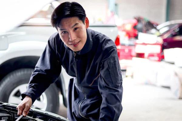 亚洲英俊的机械师 身穿制服 与汽车引擎一起工作 汽车技师在汽车维修车间检查客户汽车的维修引擎系统 — 图库照片
