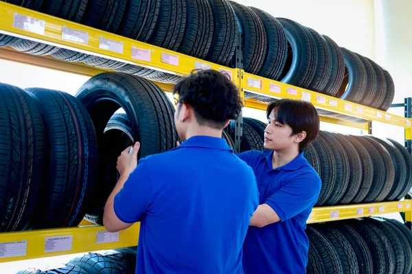 stock image Two auto mechanic Asian man checking wheel tires at vehicle repair service shop together, men working in garage, car service technician checking warehouse stock at automobile service center shop.