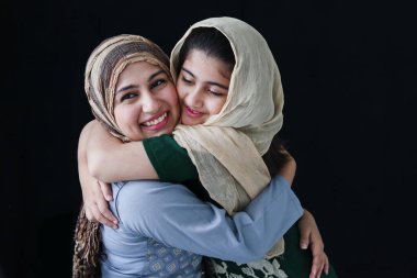 Mutlu gülümseyen, güzel gözlü, tesettürlü Müslüman bir kız. Annesine sarılan geleneksel bir eşarp takıyor. Anne ve kızının sıcak sevgisi..