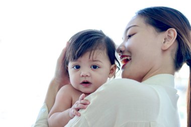 Mutlu gülümseyen bebek anne omuzlarında beyaz arka planda, anne kucağında ve kucağında küçük tatlı kız çocuğu, ebeveyni kucaklayan kız çocuğu, ailede sevgi, çocukluk bakımı ve annelik