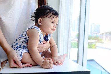 Mutlu gülümseyen bebek portresi pencerenin yanında oturan annesinin kucağında, küçük kız çocuğunun manzaraya bakan annesinin kucağında, tatlı kızının kucağında, ailede sevgi dolu bir çocuk..