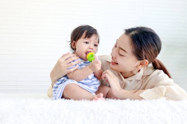 Mutlu bebek bebek ve anne oturma odasında pofuduk beyaz halı döşemesine oturur, küçük kız ve anne oyuncaklarla oynar, ebeveynler çocuğa bakar, evde bebeğe bakar, ailede aşık olur..