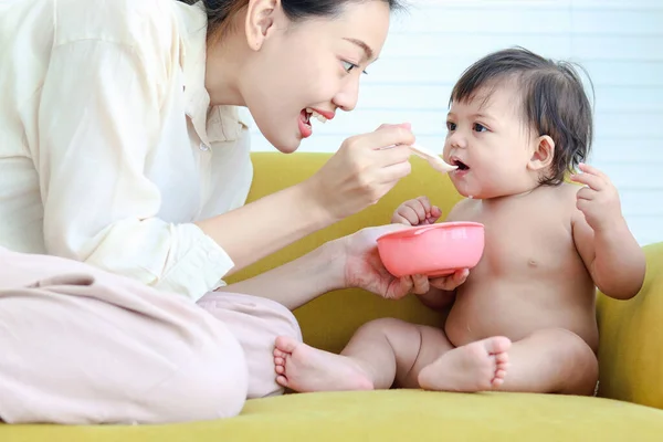 Mãe Alimenta Pequena Menina Bonito Enigma Bebê Filha Sofá Amarelo — Fotografia de Stock