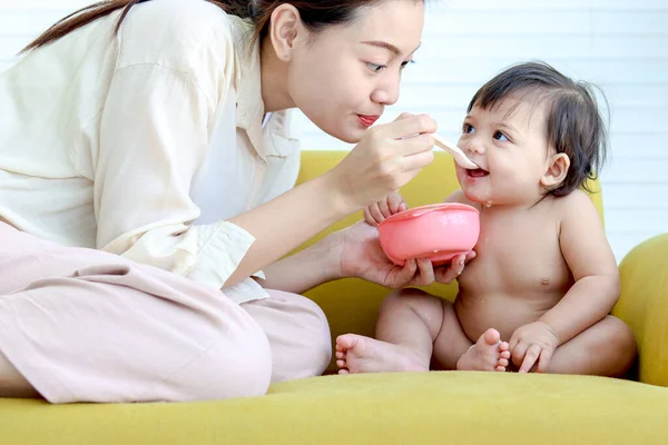 Madre Alimenta Pequeña Niña Linda Toddle Bebé Hija Sofá Amarillo —  Fotos de Stock