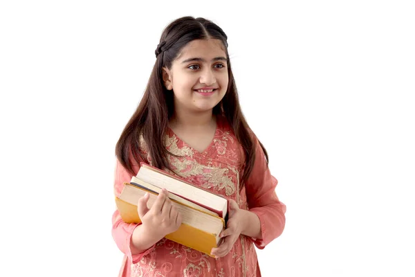 stock image Portrait of happy smiling Indian school girl child with long hair and beautiful eyes wearing traditional dress costume, holding books isolated on white background, Asian female kid education.