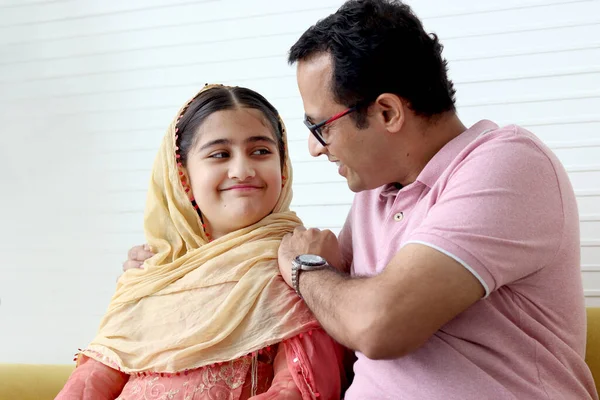 インドのイスラム教徒の娘女の子とともに伝統的なヒジャーブスカーフで座っています彼女の父でリビングルーム 笑顔かわいい子供と一緒に時間を過ごすお父さんとともに自宅で お父さん抱擁子供 幸せな素敵な家族 — ストック写真