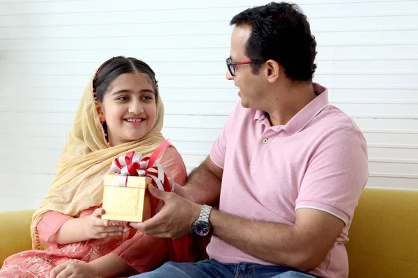 幸せな父の日 伝統的なヒジャーブスカーフを持つインドのかわいい娘は 自宅のリビングルームで校正のための父にプレゼントボックスを与え 驚くべきお父さん 一緒に幸せな家族の時間を過ごす — ストック写真
