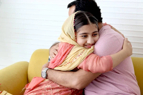 インドのイスラム教徒の娘女の子とともに伝統的なヒジャーブスカーフで座っています彼女の父でリビングルーム 子供抱擁彼女のお父さん 笑顔かわいい子供支出時間とともにお父さんと一緒に家 幸せな素敵な家族 — ストック写真