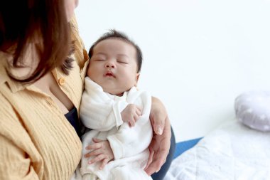 Anne, yeni doğmuş bebeği kucağına alıp yatak odasında onunla oynuyor. Anne ve çocuk birlikte vakit geçiriyorlar. Anne, baba, çocuk, şişman vücutlu şişman bir anne..