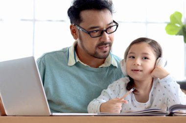 Babası tatlı bir kıza ev ödevi yapmayı öğretiyor, evde e-öğrenim için dizüstü bilgisayar kullanıyor, mutlu aile babası ve çocuğu eğitim ve internet araştırması için birlikte zaman geçiriyor..
