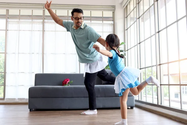 可爱的小女孩与年轻而快乐的英俊爸爸一起穿着漂亮的裙子跳舞 爸爸试图训练他的女儿跳芭蕾舞 快乐的家人在一起度过时光 父亲节快乐 — 图库照片
