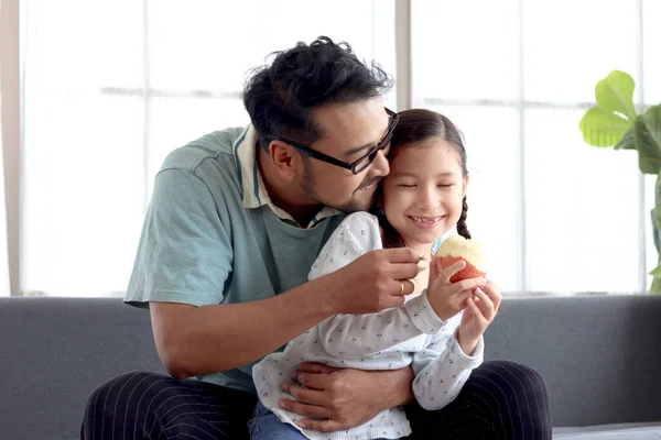 可爱的小女孩和她的爸爸坐在客厅的沙发上 一起玩 一起吃苹果 可爱的家人 爸爸和女儿一起呆在家里 照顾孩子 父亲节快乐 — 图库照片