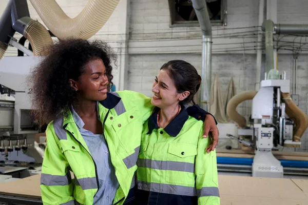 在建筑工地工作的两名漂亮的工业女机械工程师 身穿安全背心的年轻卷发女工 与她的朋友同事拥抱在一起 — 图库照片