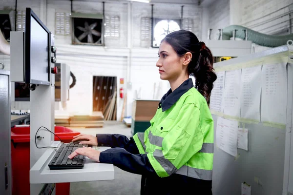 美丽的工业女机械师穿着安全背心 利用计算机操作制造厂的机械 女工在工厂的机器上工作 — 图库照片