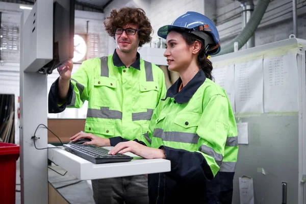 两名女工穿着安全背心 穿着漂亮的工业女机械师 一边用电脑操作机器 一边和工厂的男同事商量 一边和机器一起工作 — 图库照片