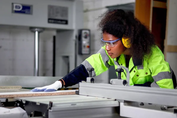 非洲女工业工人 身穿安全背心和防护耳机 与锯木机合作 女工程师在Cnc木工制造家具厂工作 — 图库照片