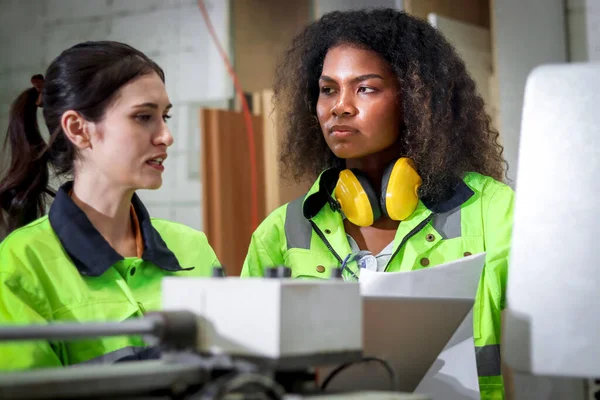 非洲工业卷发女工穿着安全背心与她在Cnc木工家具厂的女同事讨论工作场所的两名女机械工程师 — 图库照片