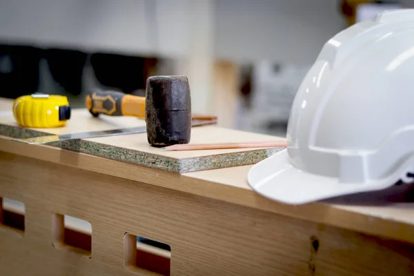 ホワイトアンチノック安全ヘルメットと職場での多くの大工ツールと木製のテーブルの上のゴムハンマー Cnc木工家具工場の設備 — ストック写真
