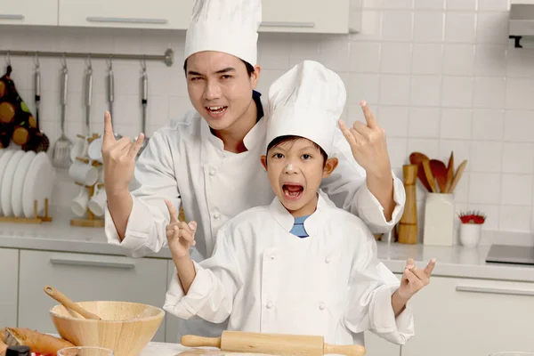 Happy Azjatycki Syn Ojciec Mundurze Szefa Kuchni Kapeluszem Pokazując Rock — Zdjęcie stockowe