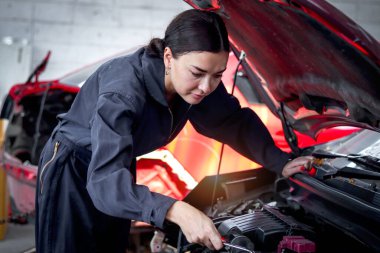 Garajda motorlu araçla çalışan güzel kadın otomobil tamircisi, otomobil tamirhanesinde müşteri arabasını kontrol eden ve tamir eden araba tamircisi,.