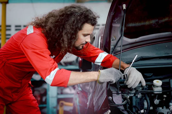 Dlouhé Vlasy Hezký Mechanik Muž Červené Uniformě Pracuje Motorovým Vozidlem — Stock fotografie