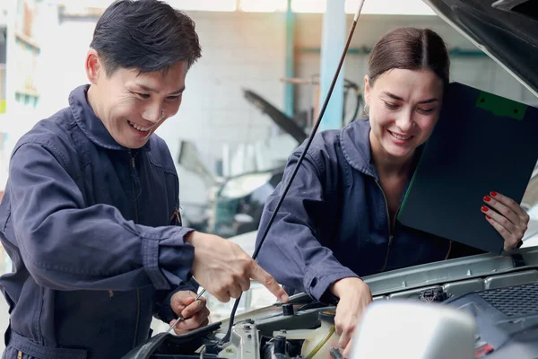 快乐的机修工男女机修工在车库里一起工作时谈论着 两名汽车机修工在汽车维修服务商店修理顾客的汽车 — 图库照片