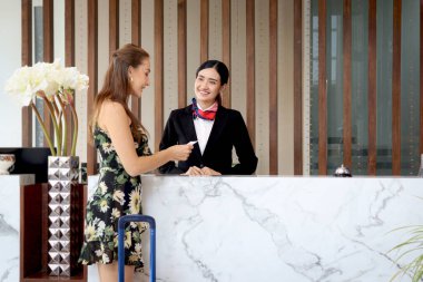 Güzel gülümseyen Asyalı kadın resepsiyonist turist kadın müşteriye anahtar kartı veriyor, resepsiyondaki bayan personel tatil tatilinde otele giriş yapmasına yardım ediyor..