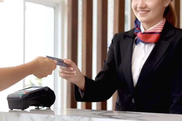 Female receptionist hand reaching out for receiving credit card form customer guest at hotel reception counter desk, woman staff getting paid by credit card,  service hotel and payment concept.