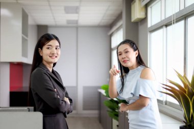 İki mutlu Asyalı güzel bayan memur, iş yerinde iş yerinden ayrılırken, iş yerinde iş arkadaşlarıyla iletişim kurarken, iş yerinde birlikte tartışan kadın personel.