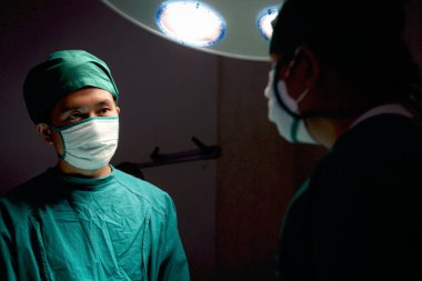 Profesyonel cerrah doktor, parlak ışık altında duruyor ve ameliyat için cerrahi ekipman kullanıyor. Cerrahi ekip ameliyat hastası, sağlık ve sağlık hizmetleri.