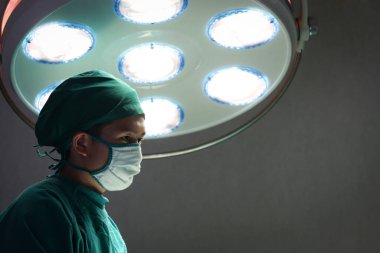 Profesyonel cerrah doktor, parlak ışık altında duruyor ve ameliyat için cerrahi ekipman kullanıyor. Cerrahi ekip ameliyat hastası, sağlık ve sağlık hizmetleri.