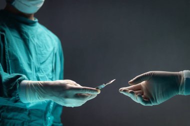 Cerrah doktor cerrahi neşter tutuyor ve ameliyathanede birbirlerine cerrahi ekipman dağıtıyorlar. Profesyonel cerrahi ekip ameliyat hastası, sağlık ve tıbbi konsept