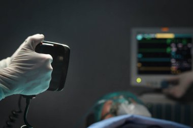 Cerrah doktorun elinde defibrilatör var. Hastanedeki hastaların hayatını kurtarmak için göğsüne kalp pompalamak için. Cerrahi ekip ameliyat için ekipman kullanıyor. Sağlık ve Tıp Konsepti.