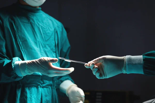 Surgeon doctor holding surgical scissors and passing surgical equipment to each other in the operating room at hospital. Professional surgical team operating surgery patient, healthcare and medical.