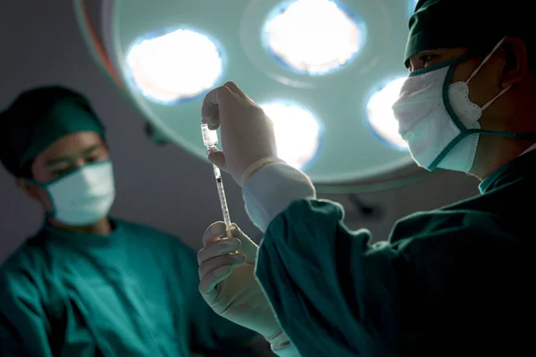 专业外科医生手持注射器 站在明亮的灯光下 在医院手术室使用外科设备做手术 外科小组手术病人 医疗保健医疗 — 图库照片