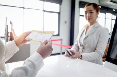 Havaalanı terminalindeki bilgileri kontrol etmek, tatilde seyahat etmek ya da iş seyahatinde seyahat etmek için seyahat kartı alan yolcu hizmetleri görevlisi kadın yolcudan biniş kartı alıyor..