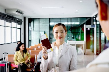 Mutlu gülümseyen güzel Asyalı kadın yolcu havaalanı terminalinde yolcu geçmişi bulanık seyahat, tatil tatili ya da iş seyahati için bekleyen yolcu geçmişi ile pasaport gösteriyor.