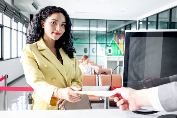 Красивая женщина-путешественница дает паспортный посадочный талон сотрудникам службы обслуживания пассажиров для проверки информации при регистрации в терминале аэропорта, путешествия на отдых или деловой поездки.