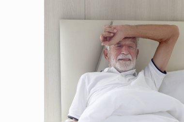 Erkek kıdemli hasta hastane yatağında yatıyor. Yaşlı bir adam kendini hasta hissediyor, evde dinlenme ihtiyacı duyuyor, hasta bir adamın başı ağrıyor, acı yüzünden elini alnına koyuyor. Yaşlılar sağlık hizmeti kavramı