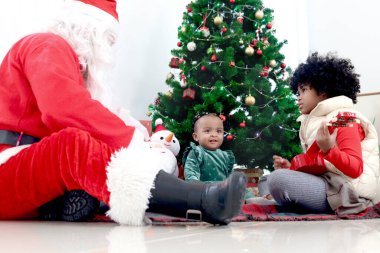 Noel ağacının altında Noel Baba ve kız kardeşi olan mutlu Afrikalı kız Noel Baba, Noel Baba 'nın iyi çocuklara hediye kutlaması, mutlu Noel bayramı kutlaması, mutlu çocukluk..