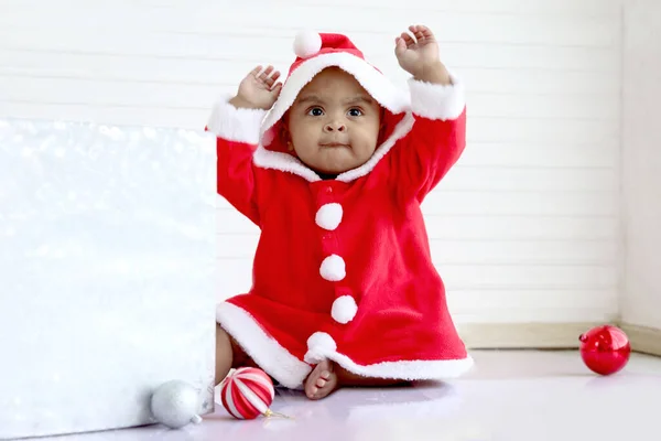 Afrikaans Baby Kind Rood Kerstman Kostuum Met Bal Ornament Zitten Stockafbeelding