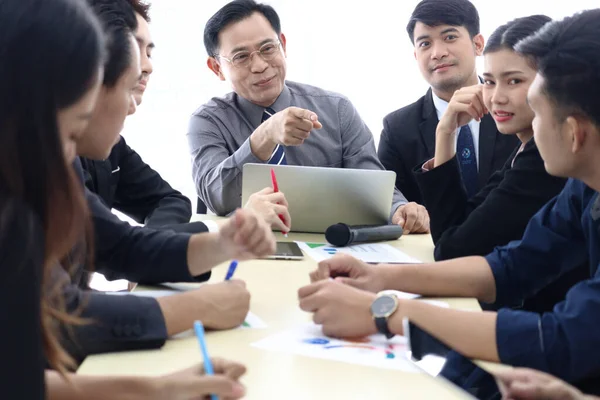 Businesspeople at conference, happy smiling senior businessman pointing at someone to ask question at group meeting. Elderly boss discussing with teammate, company teamwork brainstorming meeting.