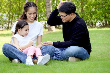 Mutlu bir aile yeşil çimenlerde oturuyor, yaz bahçesinde eğleniyor ve birlikte vakit geçiriyor. Arka bahçede babasıyla oynarken annesinin kucağında oturan tatlı bir kız çocuğu. Aile sevgisi kaynaşması.