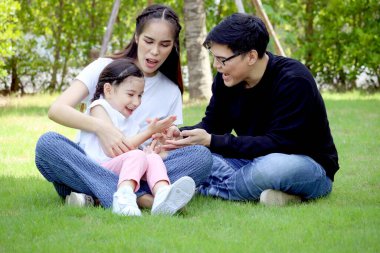 Mutlu bir aile yeşil çimenlerde oturuyor, yaz bahçesinde eğleniyor ve birlikte vakit geçiriyor. Arka bahçede babasıyla oynarken annesinin kucağında oturan tatlı bir kız çocuğu. Aile sevgisi kaynaşması.