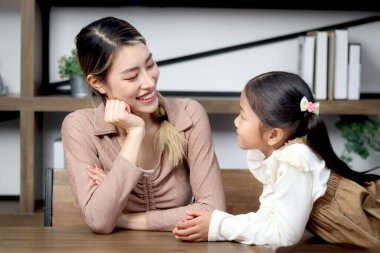 Mutlu bir aile evde birlikte vakit geçiriyor, Asyalı mutlu bir anne tatlı kızına sevgi dolu, sevimli ve mutlu aile ilişkileriyle bakıyor. Ebeveynler çocuğa bakar..